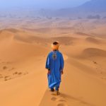 Man from a tour operator in Morocco walking in Erg Chebbi Dunes